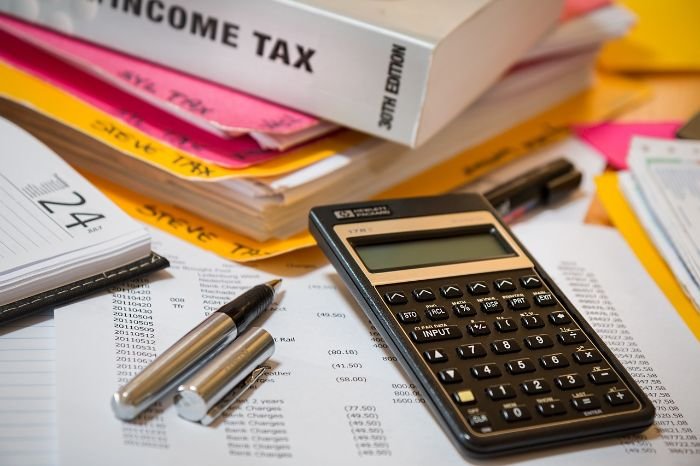 A calculator, pens, and financial documents laid out on a desk, symbolizing the cost-benefit analysis of investing in professional cleaning services for long-term savings and property value maintenance.