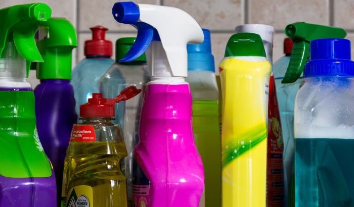 A variety of colorful cleaning spray bottles lined up, ready to be used for disinfecting surfaces during post-illness home cleaning.