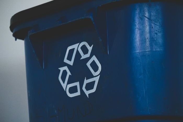 A close-up of a worn-out blue recycling bin with the recognizable recycling symbol, highlighting the importance of sorting and recycling household waste.