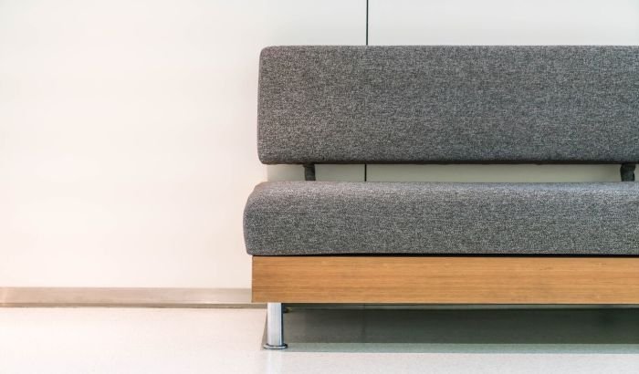 A clean and well-maintained grey fabric upholstered bench against a white wall, demonstrating the result of deep cleaning techniques for furniture.
