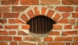 A close-up view of a vintage brick wall with a vent, highlighting the importance of proper ventilation during the cleaning process.