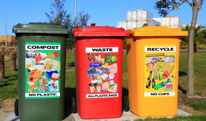 Three color-coded waste bins labeled 'COMPOST,' 'WASTE,' and 'RECYCLE' promoting proper household waste segregation to support environmental health.