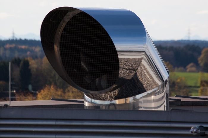 A modern rooftop ventilation unit against a clear sky, representing advanced air purification and the significance of ventilation in maintaining indoor air quality.