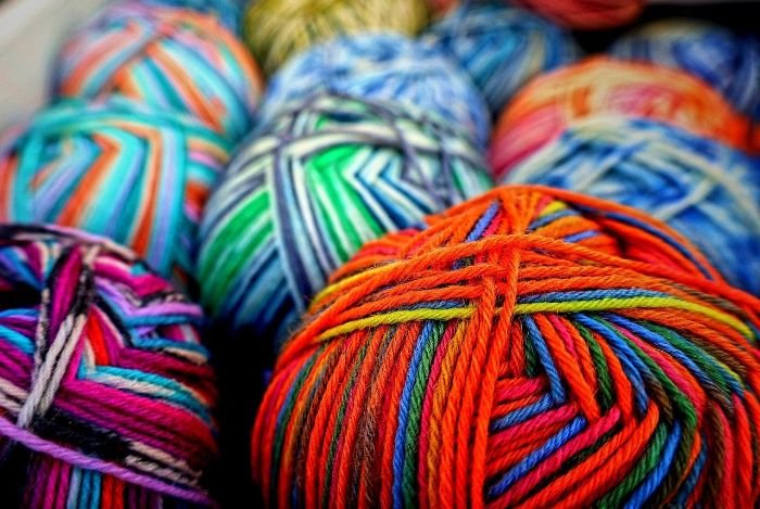 Close-up of multi-colored yarn balls with vibrant hues and intricate patterns, representing the diversity and delicacy of materials like silks and wools that require special care for stain removal.