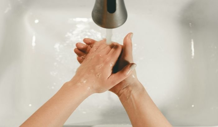 A person thoroughly washing their hands under a running faucet, symbolizing the critical practice of hand hygiene as a cornerstone of maintaining cleanliness and preventing the spread of germs.