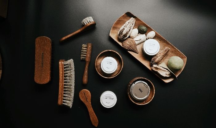 Assortment of metal brushes and eco-friendly cleaning products on a dark surface, symbolizing the preparatory steps for rust stain removal.