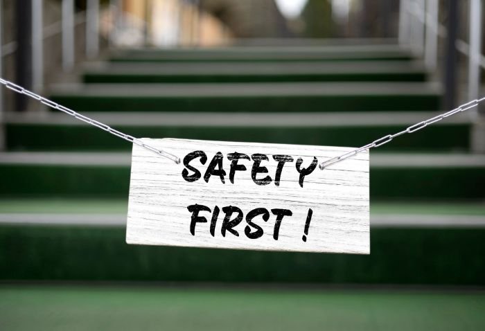 A "Safety First" sign suspended by chains, prominently displayed against the backdrop of stairs, emphasizing the priority of safety in the workplace.