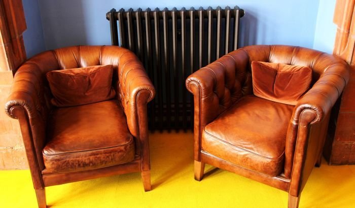 Two classic leather armchairs in a room with a bright yellow carpet, exemplifying the elegance of well-maintained leather furniture that may require stain removal care.