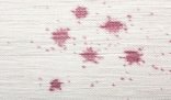 Close-up of a white carpet with deep pink stains illustrating the challenge of dealing with stubborn carpet stains.