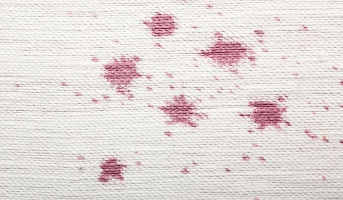 Close-up of a white carpet with deep pink stains illustrating the challenge of dealing with stubborn carpet stains.