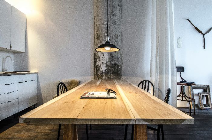 A modern wooden table under a hanging light, setting a perfect scene for discussing effective cleaning methods for oil and grease stains on wood surfaces.