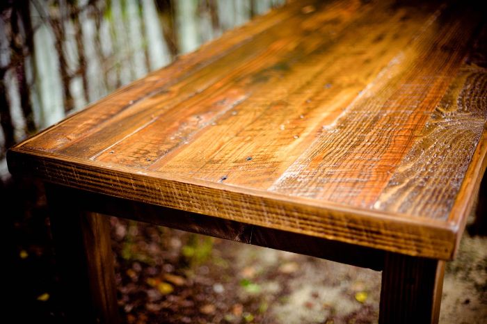 Sunlight glints off a polished wooden table, illustrating the proper start to a cleaning routine with the focus on maintaining the integrity of the wood's surface.