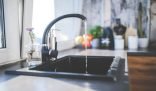 A clean kitchen sink with running water, illustrating the concept of quickly cleaning your kitchen in under 15 minutes.