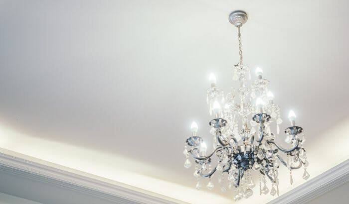 A crystal chandelier hanging from a ceiling, illustrating the challenge of cleaning hard-to-reach places.