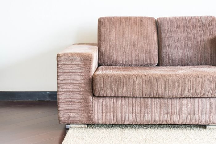 Brown sofa against a white wall, representing the topic of removing ink stains from different types of furniture materials.