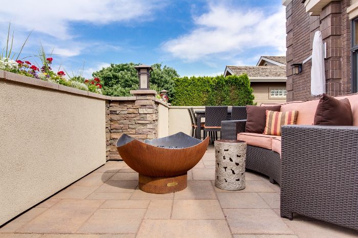 Quick Tips for Tidying Outdoor Spaces 3 A well-kept patio area with a white bench, surrounded by green plants and flowers, illustrating the importance of regular cleaning to maintain its appearance and functionality.