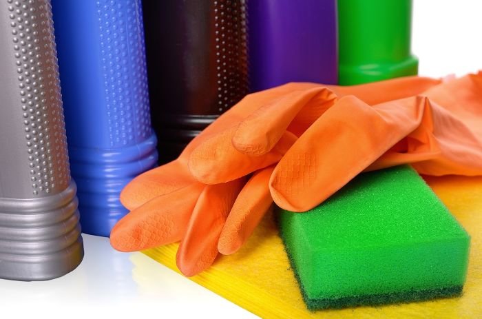 Cleaning supplies, including rubber gloves, a sponge, and cleaning bottles, illustrating the importance of gathering all necessary tools before starting a quick clean.