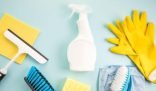 An array of DIY cleaning tools including a spray bottle, yellow gloves, squeegee, and brushes on a light blue background, highlighting essential equipment for safe and effective home cleaning.