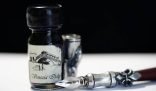 Bottle of ink and an old-fashioned fountain pen, representing the challenge of removing ink stains from clothes and furniture.