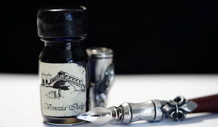 Bottle of ink and an old-fashioned fountain pen, representing the challenge of removing ink stains from clothes and furniture.
