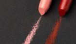 Close-up of pink and red lipstick stains on a black surface, illustrating the topic of removing makeup stains from clothes.