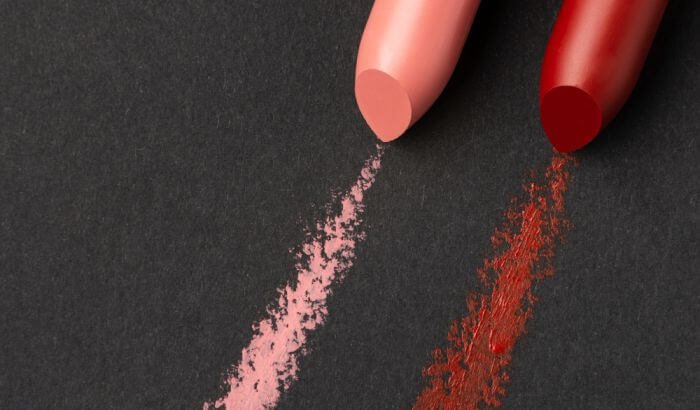 Close-up of pink and red lipstick stains on a black surface, illustrating the topic of removing makeup stains from clothes.