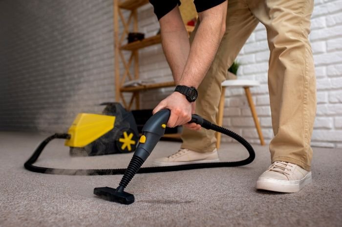 A close-up of a man using a powerful vacuum cleaner on a carpet, highlighting the crucial role of deep cleaning in removing dirt and improving the overall environment of a home.