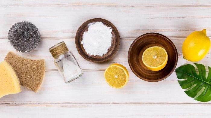 Natural cleaning agents including baking soda, lemon, and sponges, illustrating safe, chemical-free options for cleaning pet toys and accessories.