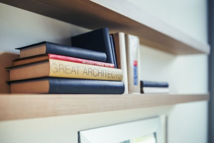 Books neatly arranged on wooden shelves, illustrating the importance of dust prevention in maintaining clean and organized spaces.