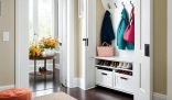 A well-organized entryway with coats hung neatly, a shoe rack filled with shoes, and a table with a vase of fresh flowers, presenting a welcoming and tidy space for guests.