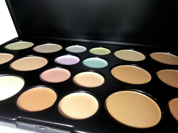A makeup palette with various shades and colors, illustrating the need for different methods to remove specific makeup products from clothes.