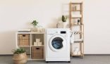 A well-organized laundry room featuring a washing machine, shelves with baskets, plants, and neatly stacked towels, illustrating efficient and streamlined laundry processes.