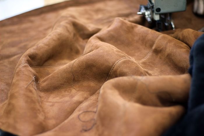 Close-up of a suede material under a sewing machine, emphasizing the texture and nuances of suede fabric, suitable for discussing effective stain removal techniques in a blog post.