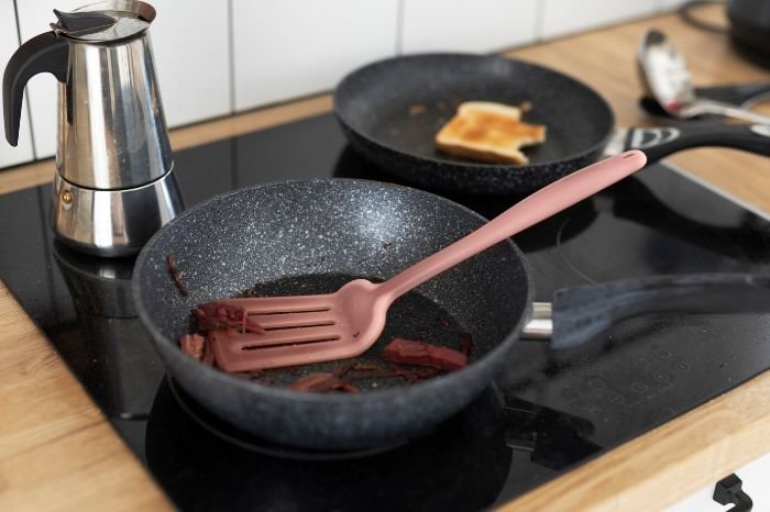 Kitchen scene with large frying pans and cookware, illustrating tips for handling and cleaning large items and cookware effectively.