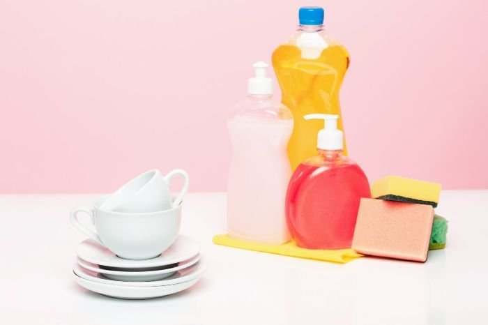 Various dishwashing products including dish soap, sponges, and plates, illustrating essential tools and products for quick and efficient dishwashing.