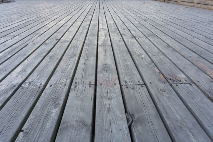 Wide-angle view of a weathered wooden deck, illustrating the texture and condition before deep cleaning, suitable for a guide on maintaining and cleaning wood and composite deck materials.