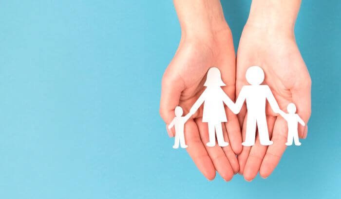 Hands holding a paper cutout of a family, symbolizing child-safe cleaning habits every parent should know.