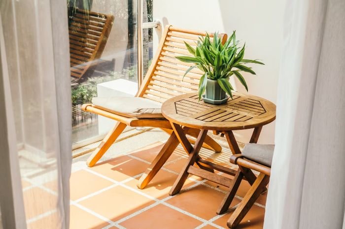 Clean and tidy patio with wooden furniture and a plant, illustrating the importance of regular cleaning and maintenance for outdoor spaces like patios and decks.