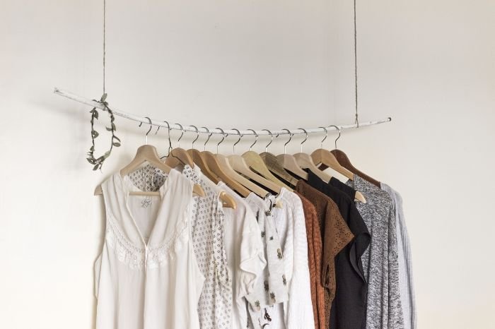 A neatly organized closet with various clothes hanging on wooden hangers, illustrating effective methods for organizing drawers and closets to streamline your morning routine.
