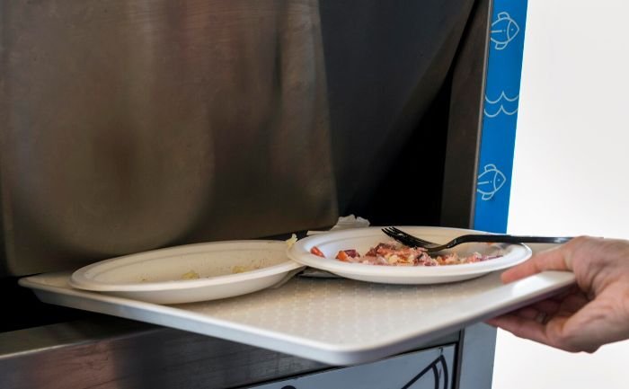 Plates with food scraps on a tray, illustrating the process of soaking and scrubbing to remove stains from plastic items.