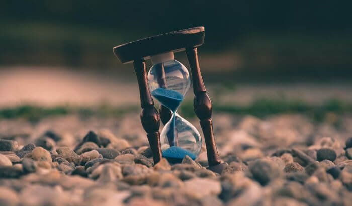 An hourglass standing on pebbles, symbolizing the importance of time management for maintaining a clean and healthy home efficiently.