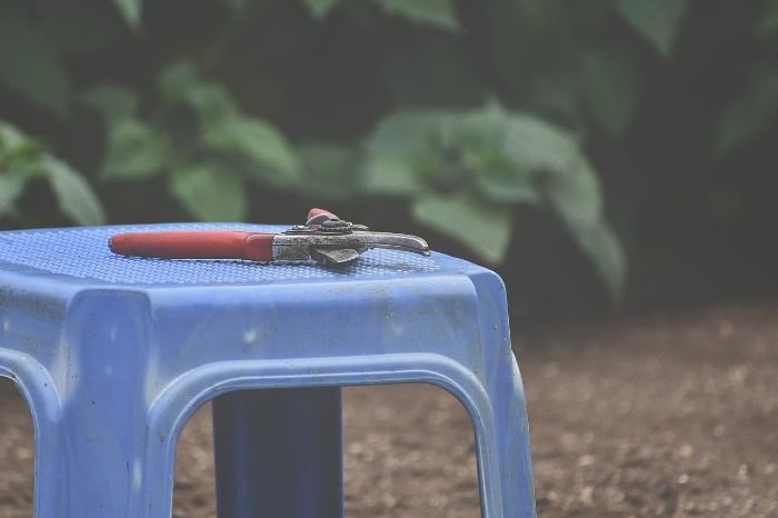A pair of pliers on a blue plastic stool, illustrating the importance of understanding the causes of stains on plastic items.