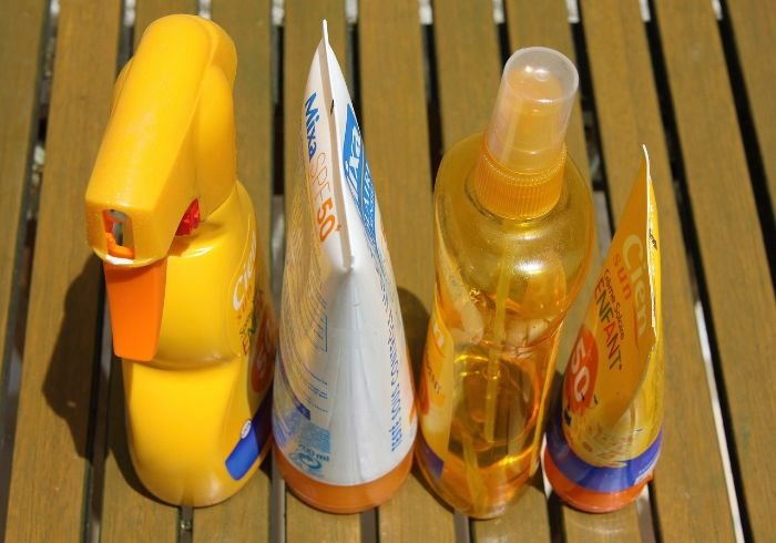 Various sunscreen bottles on a wooden surface, highlighting the importance of understanding sunscreen stains and why they are tough to remove from clothing.