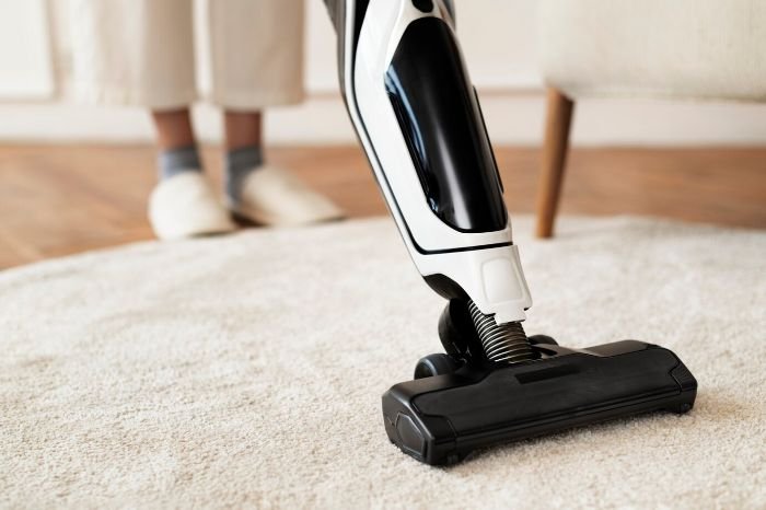 Person using a vacuum cleaner on a carpet, following tips for perfect end of tenancy cleaning and ensuring a smooth return of the deposit.