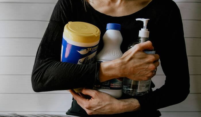 Person holding various cleaning supplies, illustrating the challenging aspects of end of tenancy cleaning and how professionals handle them.