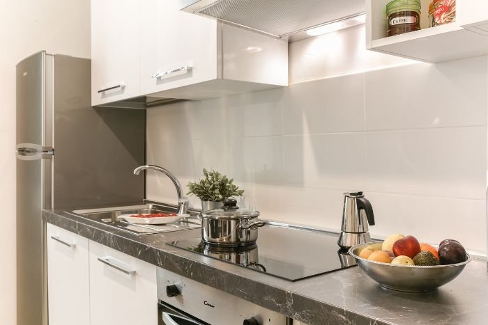 A clean and organized kitchen countertop with a shiny stovetop, a bowl of fruit, and a few kitchen items, illustrating the effectiveness of decluttering in short, manageable 5-minute sprints.