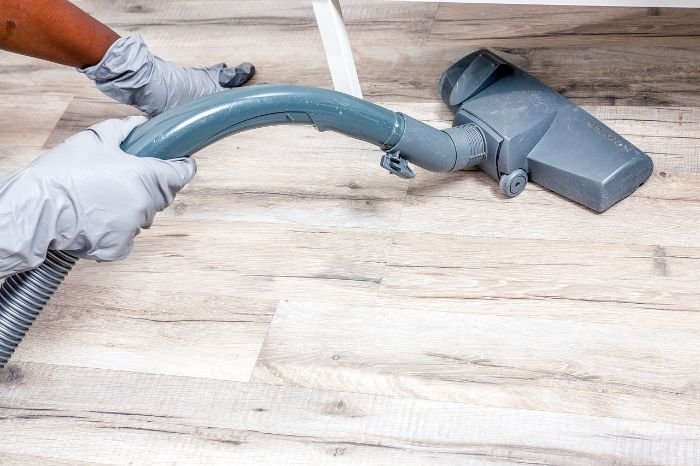 A person vacuuming a floor as part of daily and weekly cleaning tasks to maintain a clean and inviting home environment.