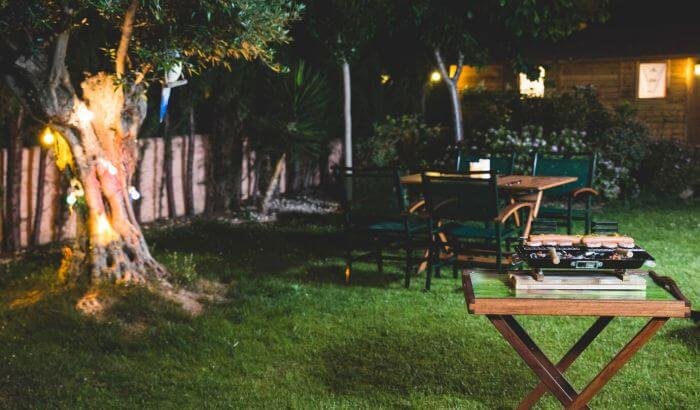 A beautifully lit garden in London at night, showcasing creative garden lighting ideas with illuminated trees and outdoor dining area, perfect for enhancing the ambiance of London homes.