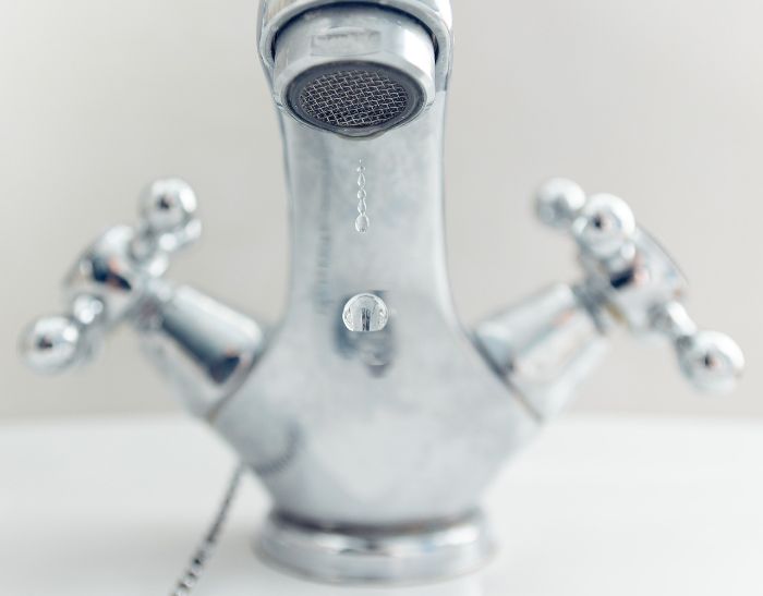 Common Mistakes to Avoid During End of Tenancy Cleaning in London 3 Close-up of a bathroom faucet with a water droplet, highlighting the importance of removing limescale and ensuring thorough cleaning to avoid common mistakes during end of tenancy cleaning.