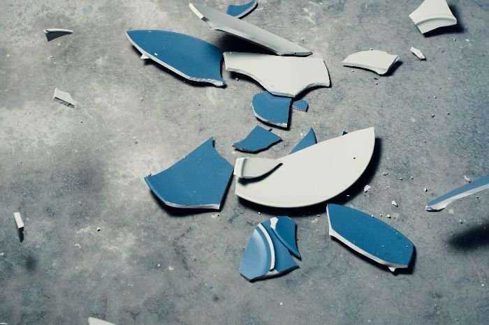 Broken blue and white ceramic pieces on the floor, illustrating the importance of insurance for end of tenancy cleaning services.